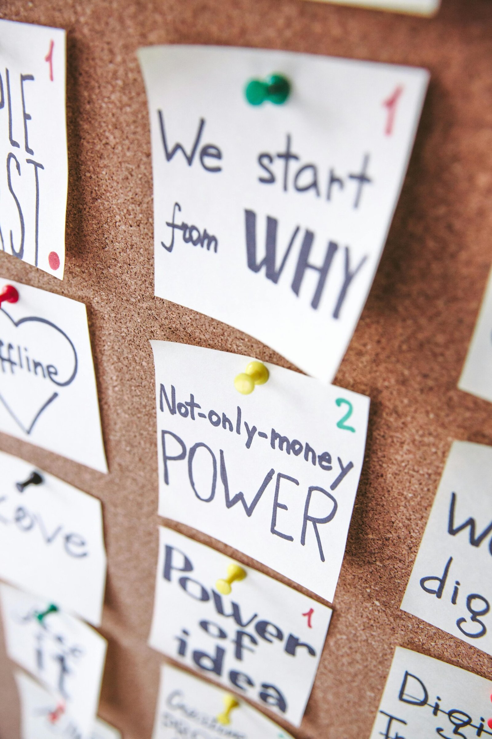 Close-up of motivational sticky notes with messages on a cork board.